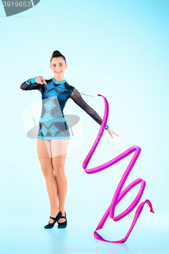 Image of The girl doing gymnastics dance with colored ribbon on a blue background