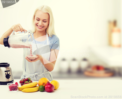 Image of smiling woman with blender and fruit milk shake