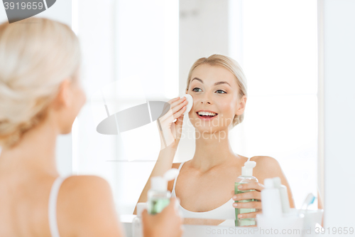 Image of young woman with lotion washing face at bathroom