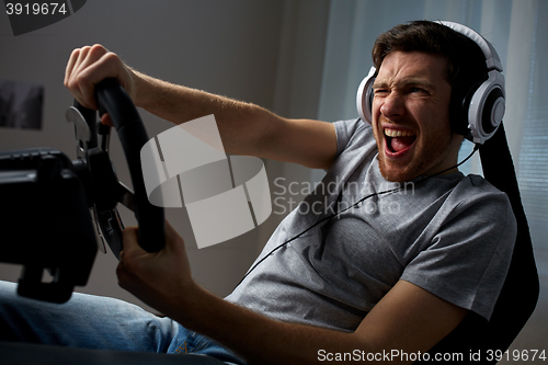 Image of man playing car racing video game at home