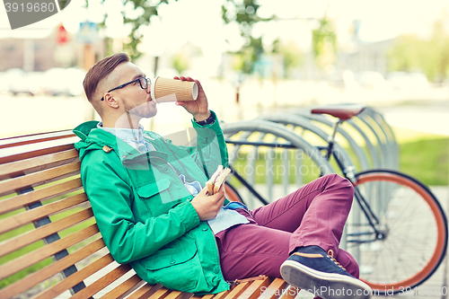 Image of happy young hipster man with coffee and sandwich