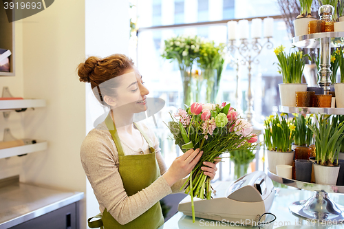 Image of smiling florist woman making bunch at flower shop