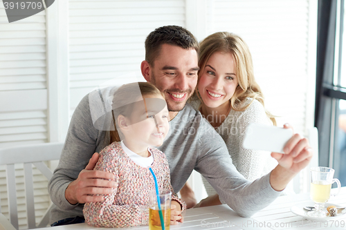 Image of happy family taking selfie at restaurant