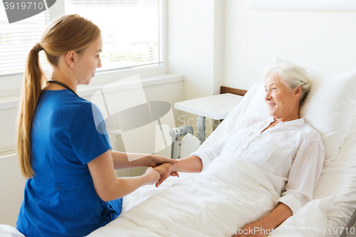 Image of doctor or nurse visiting senior woman at hospital