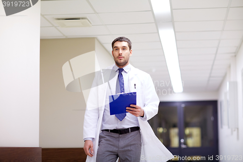 Image of doctor with clipboard walking along hospital