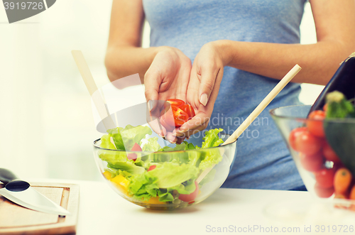 Image of close up of woman cooking vegetable salad at home