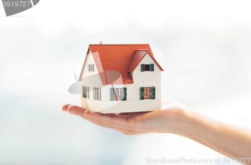 Image of close up of hands holding house or home model