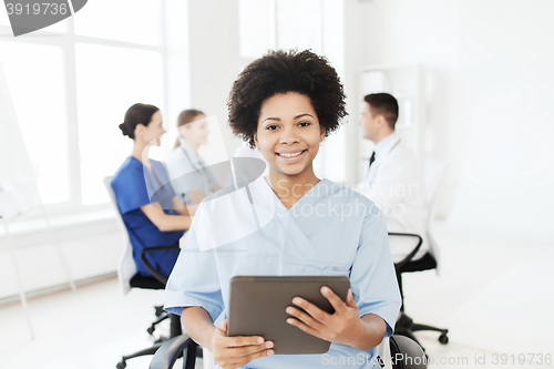 Image of happy nurse with tablet pc over team at hospital