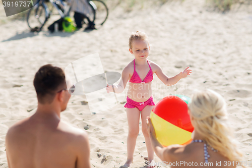 Image of happy family playing with inflatable ball on beach