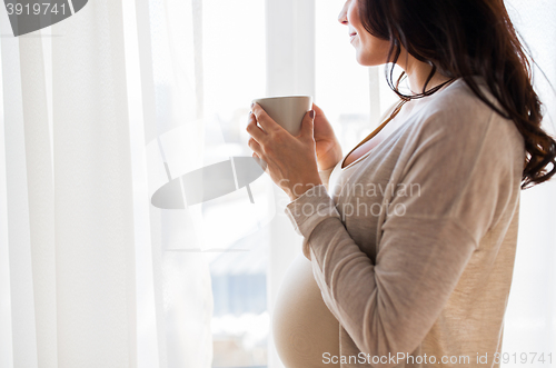 Image of close up of pregnant woman with tea cup at window