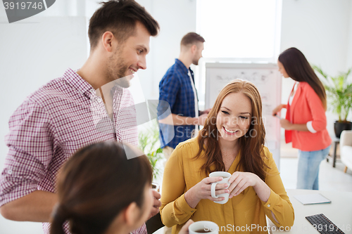 Image of happy creative team drinking coffee at office