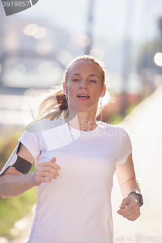 Image of sporty woman running  on sidewalk