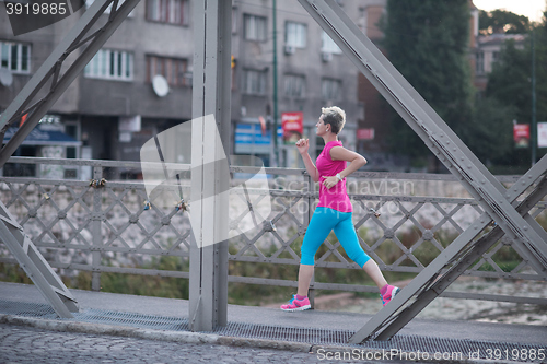 Image of sporty woman running  on sidewalk