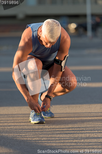 Image of Man tying running shoes laces