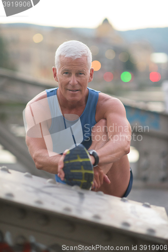 Image of handsome man stretching before jogging