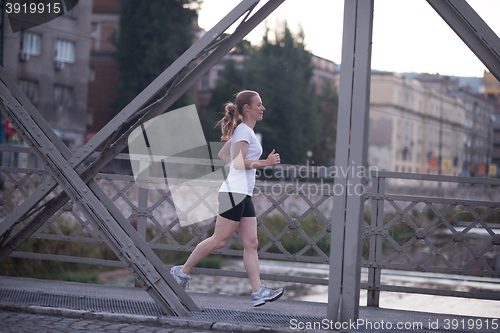 Image of sporty woman running  on sidewalk