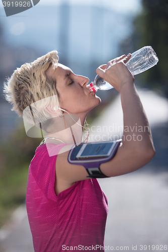 Image of woman drinking  water after  jogging