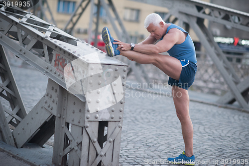 Image of handsome man stretching before jogging