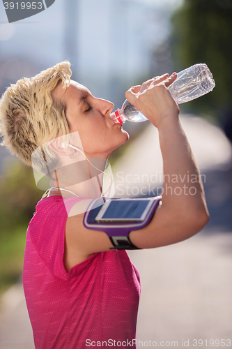Image of woman drinking  water after  jogging