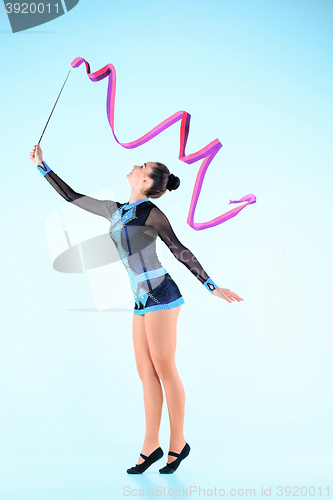 Image of The girl doing gymnastics dance with colored ribbon on a blue background