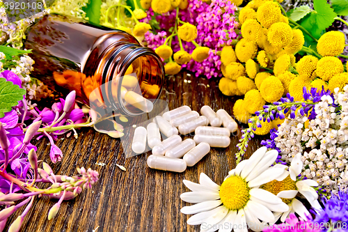 Image of Capsules in brown jar with flowers on board