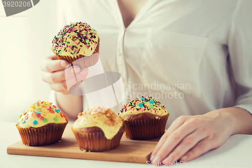 Image of close up of woman with glazed cupcakes or muffins