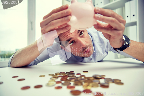 Image of businessman with piggy bank and coins at office