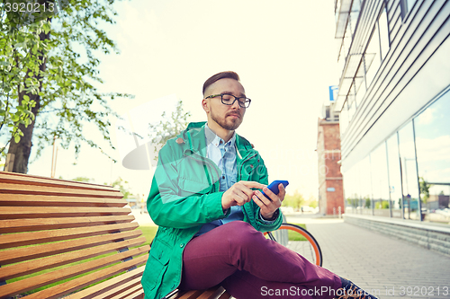 Image of happy young hipster man with smartphone and bike