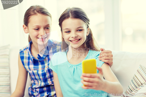 Image of happy girls with smartphone taking selfie at home