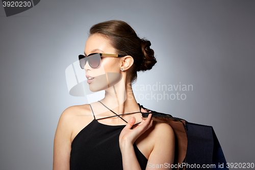 Image of happy woman in black sunglasses with shopping bags