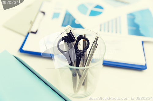 Image of close up of cup with scissors and pens at office