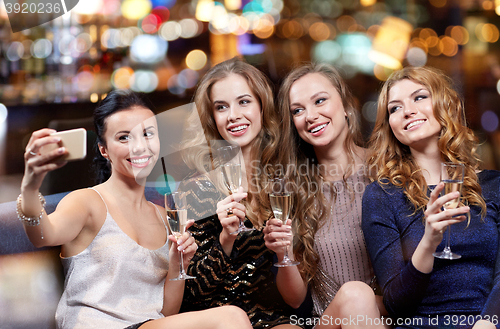 Image of women with champagne taking selfie at night club