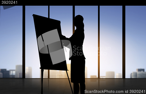 Image of silhouette of woman with flipboard over office