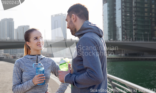 Image of smiling couple with bottles of water in city