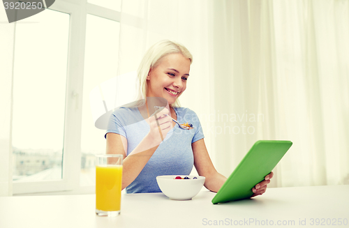 Image of woman with tablet pc eating breakfast at home