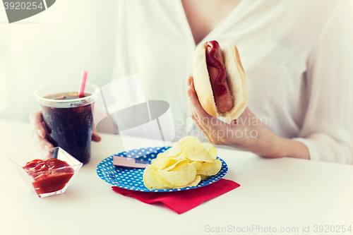 Image of close up of woman eating hot dog with cola