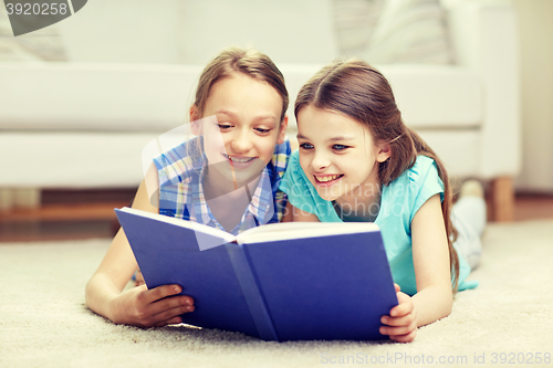 Image of two happy girls reading book at home