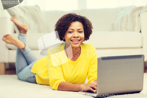 Image of happy african american woman with laptop at home