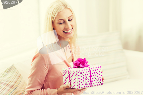 Image of smiling woman with gift box at home