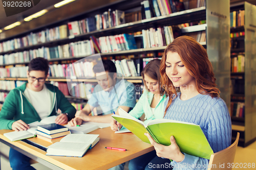 Image of happy students reading books in library