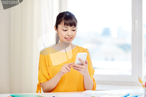 Image of happy young woman student with smartphone at home