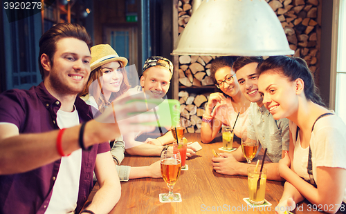 Image of happy friends with smartphone taking selfie at bar