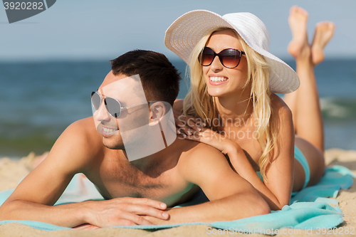 Image of happy couple in swimwear lying on summer beach