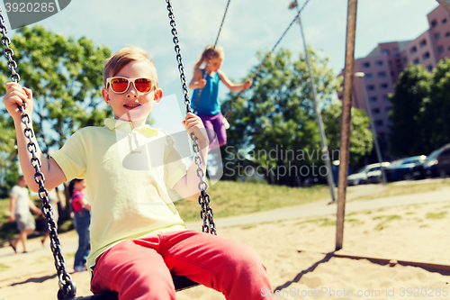 Image of two happy kids swinging on swing at playground