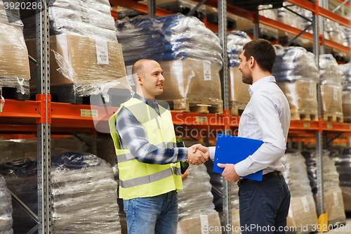 Image of worker and businessmen with clipboard at warehouse