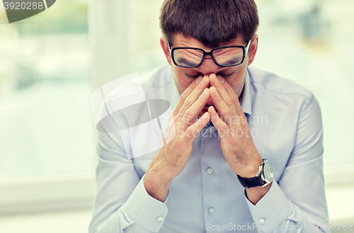Image of tired businessman with eyeglasses in office