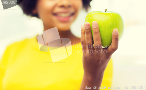 Image of happy african american woman with green apple