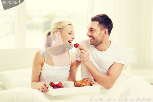 Image of happy couple having breakfast in bed at home