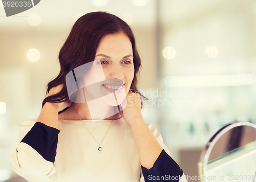 Image of happy woman choosing pendant at jewelry store