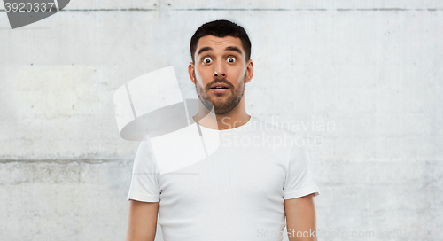 Image of scared man in white t-shirt over wall background